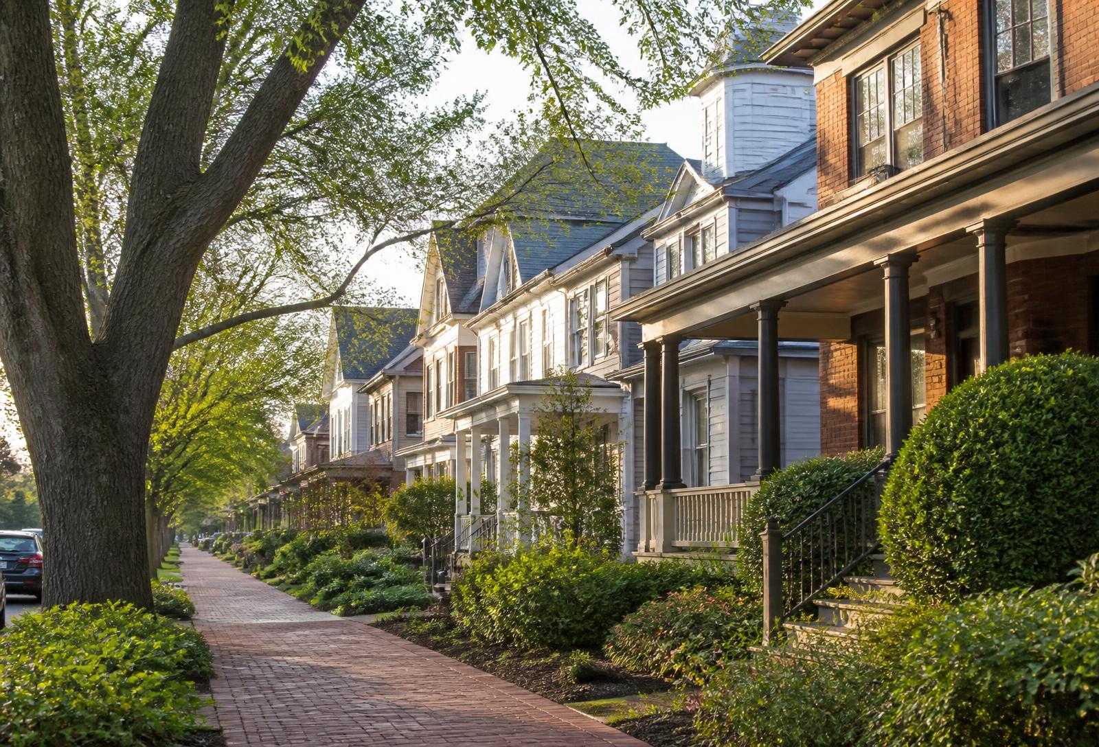 Tree-lined Evanston street of historic brick and clapboard homes with deep front porches and mature elms